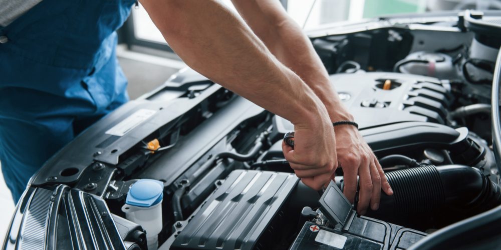 Some electronic parts. Process of repairing car after accident. Man working with engine under the hood.